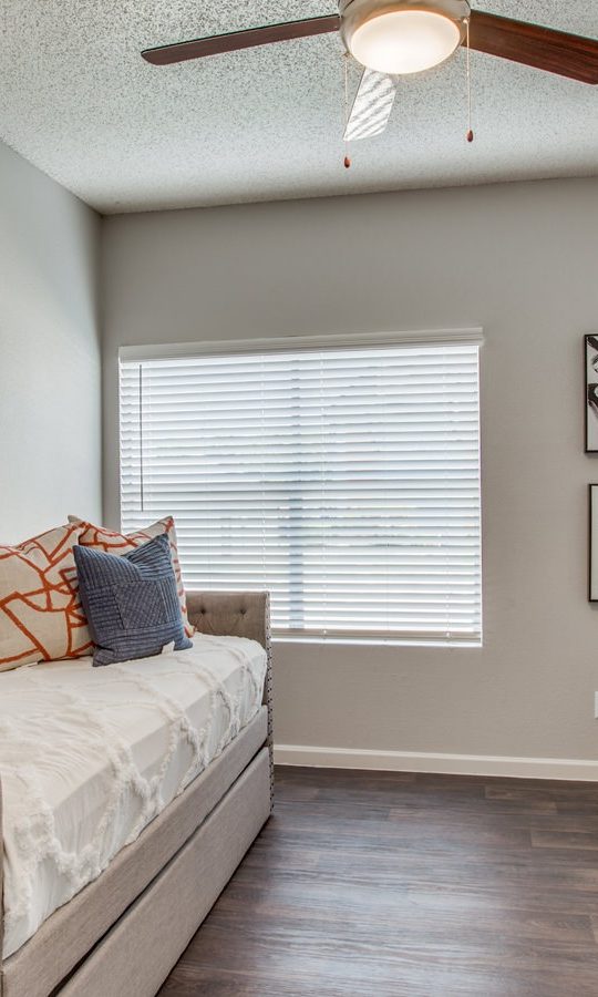 a bedroom with a bed, desk and ceiling fan at The Felix